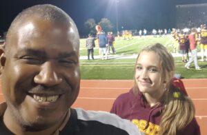 man and young lady getting their photo taken on a football track