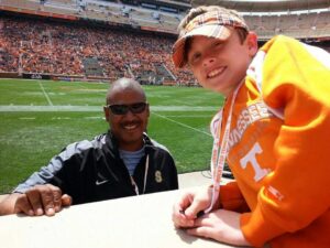 coach and young boy getting their photo taken by football field