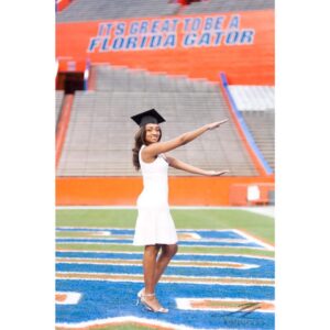 young woman graduate in cap on football field